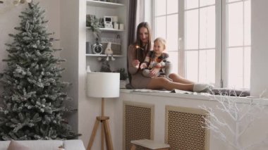 Anne ve küçük kızı yeni yıl kutlamaları için ışıltılı bir gülümsemeyle oynuyorlar, bayram sezonundan mutlular. Noel tatili ve aile birlikte..