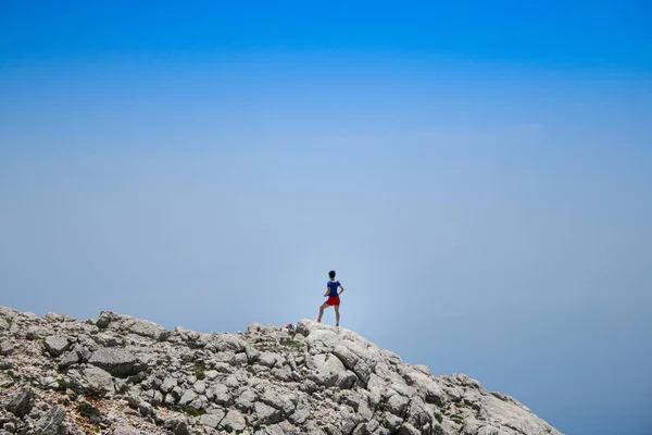 Dağın tepesinde berrak gökyüzüne karşı duran kadının dikiz görüntüsü
