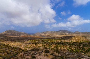 İspanya 'da Rodalquilar kasabası yakınlarındaki tipik Almerya manzarası, mavi gökyüzü ve beyaz bulutlar,.