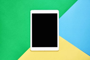 Üstten Görünüm; Tablet ile modern işyeri pastel sarı bir arka plan üzerinde yerleştirilir. Kopya alanı grafik kullanım için uygun.