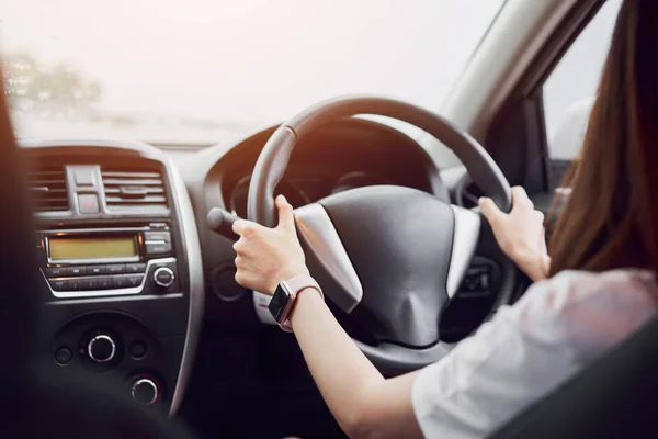 women is driving car. rear view can look to the front in same view as driver.