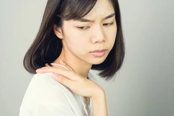 亚洲女孩穿着白色休闲连衣裙抓住那肩膀 因为辛苦工作的痛苦 或者什么东西撞到了肩膀上 在灰色背景下给出柔和的光 — 图库照片