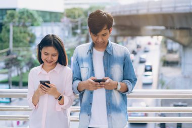 Gençlerin smartphone kullanarak ve serbest zaman üzerinde otururken gülümseyerek. teknoloji kavramı