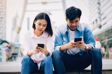 Gençlerin smartphone kullanarak ve serbest zaman üzerinde otururken gülümseyerek. teknoloji kavramı