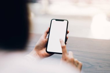 Bir smartphone tutan kadın closeup boş ekran alay. cep telefonu üzerinde kafe kullanarak. İletişim kavramı için teknoloji.