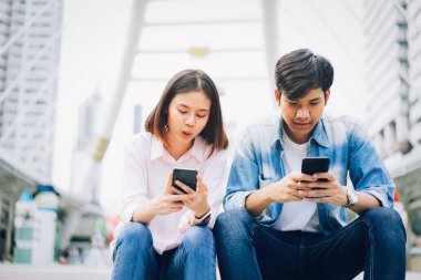 Gençlerin smartphone kullanarak ve serbest zaman üzerinde otururken gülümseyerek. teknoloji kavramı