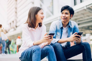 Gençlerin smartphone kullanarak ve serbest zaman üzerinde otururken gülümseyerek. teknoloji kavramı
