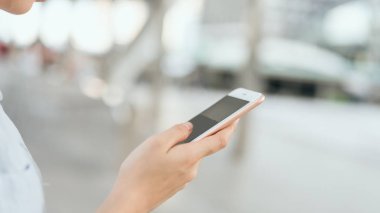 Boş zamanlarında kamusal alanlarda akıllı telefon kullanan bir kadın. Telefonu kullanma konsepti günlük hayatta gereklidir..