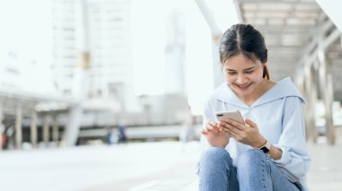 Boş zamanlarında kamusal alanlarda akıllı telefon kullanan bir kadın. Telefonu kullanma konsepti günlük hayatta gereklidir..