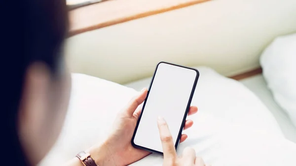 Woman using blank screen of smartphone on room, During leisure time. The concept of using the phone is essential in everyday life.