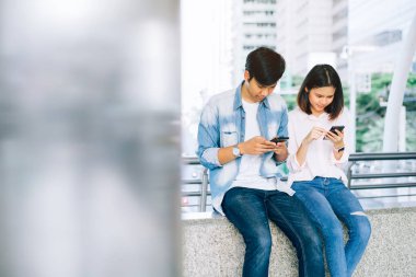 Asya genç insan smartphone kullanarak ve serbest zaman üzerinde otururken gülümseyerek. teknoloji kavramı