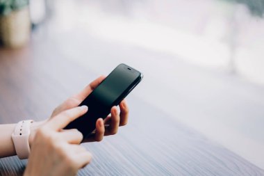 Bir smartphone tutan kadın closeup boş ekran alay. cep telefonu üzerinde kafe kullanarak. İletişim kavramı için teknoloji.