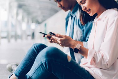 Gençlerin smartphone kullanarak ve serbest zaman üzerinde otururken gülümseyerek. teknoloji kavramı