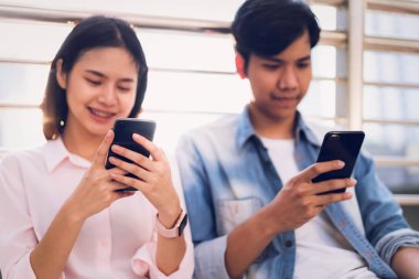 Gençlerin smartphone kullanarak ve serbest zaman üzerinde otururken gülümseyerek. teknoloji kavramı