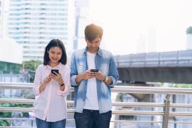 Gençlerin smartphone kullanarak ve serbest zaman üzerinde otururken gülümseyerek. teknoloji kavramı