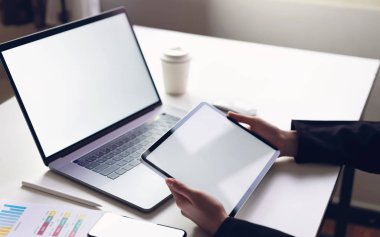 Tablet ekranı boş ve akıllı telefonlu bir kadın ürünlerinizi tanıtmak için masayı hazırlıyor. Bilgiye kolay erişim için gelecek kavramı ve eğilim interneti.