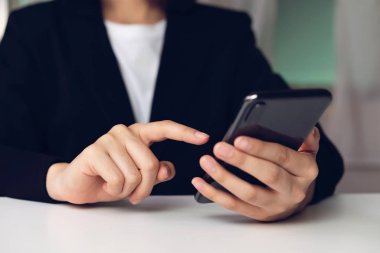 Akıllı telefon tutan, kafede cep telefonu kullanan bir kadın. İletişim kavramı teknolojisi.