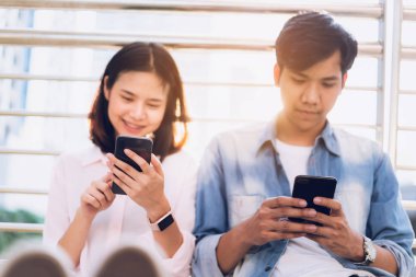 Gençlerin smartphone kullanarak ve serbest zaman üzerinde otururken gülümseyerek. teknoloji kavramı