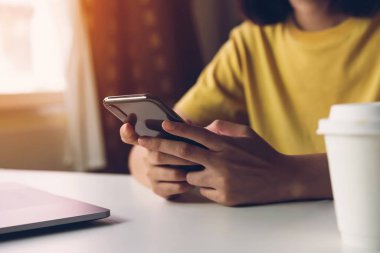 Akıllı telefon tutan, kafede cep telefonu kullanan bir kadın. İletişim kavramı teknolojisi.