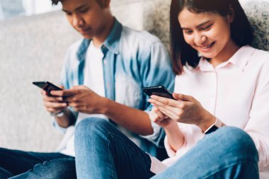 Gençlerin smartphone kullanarak ve serbest zaman üzerinde otururken gülümseyerek. teknoloji kavramı