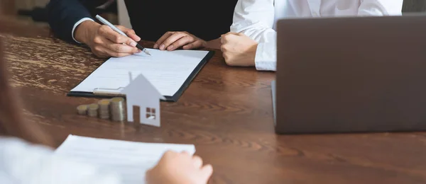 Couples signed a contract to buy a house from the broker. Coin to stack money and model house placed on the table, financial Business Growth.