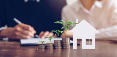 Çiftler komisyoncu bir ev satın almak için bir sözleşme imzaladı. Coin para ve model ev masaya yerleştirilen yığını, finansal Iş büyüme.