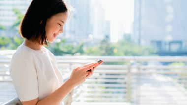 Ofis binasında akıllı telefon ve ayakta kullanarak güzel Asyalı kadın. Telefon kullanma kavramı günlük yaşamda esastır.