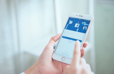 Bangkok, Tayland - 20 Ağustos 2019 : kadın el ele tutuşuyor ve apple akıllı telefonda Facebook ekranına basıyor, Sosyal medya bilgi paylaşımı ve ağ için kullanıyor.