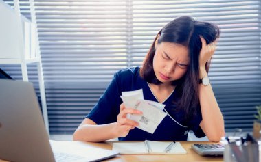 Strain yüz Asya kadın el tutan gider faturası ve ev ofis masada aylık borç faturaları hakkında hesaplama.