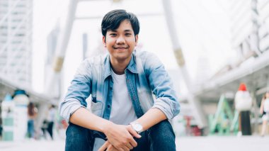 Mutlu gülümseyen ve ofis binasında oturan Genç Asyalı adam. 