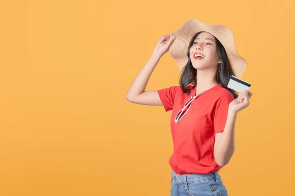 オレンジ色の背景にクレジットカードの支払いを保持する帽子を身に着けている美しいアジアの女性の良い肌 — ストック写真