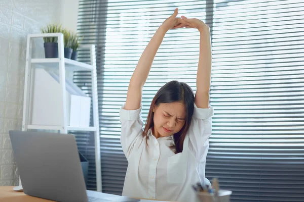 Asian business woman raise your hand above the head, to relieve pain and fatigue from hard work.