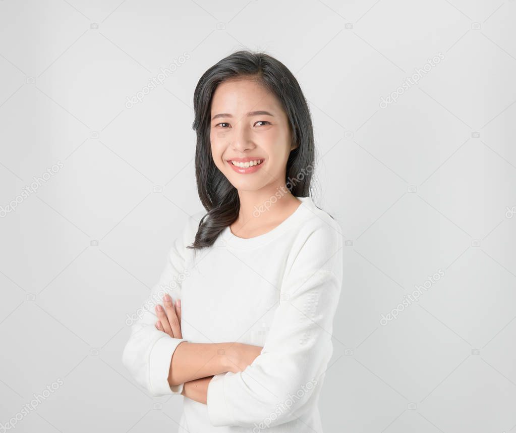 Cheerful beautiful Asian woman stand and crossed arms on gray background.