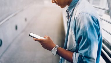 Akıllı telefon tutan bir adama yakın çekim, boş ekran maketi. Yaşam tarzında cep telefonu kullanmak. İletişim kavramı teknolojisi.