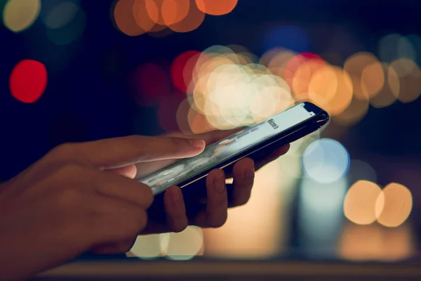 Gece atmosferik şehirde akıllı telefonu kullanmanın yumuşak odak noktası bokeh renk ışığı, boş ekranın taklidi. Yaşam tarzında cep telefonu kullanmak. İletişim kavramı teknolojisi.