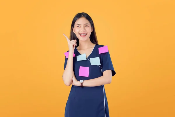 兴奋的亚洲年轻女子站在指着手指 感觉快乐与交叉的手臂对 邮政笔记在身体上 橙色背景 — 图库照片