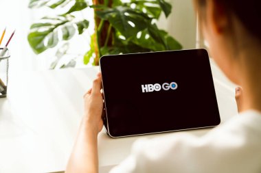 Bangkok, Tayland - 09 Ağustos 2020: HBO uygulaması olan akıllı telefonu tutan kadın. premium TV bölümleri ve filmler izlemek için yayın hizmeti.