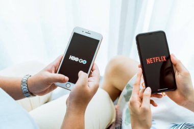 Bangkok, Tayland - 09 Ağustos 2020: HBO ve Netflix uygulamalı akıllı telefon tutan kadınlar. premium TV bölümleri ve filmler izlemek için yayın hizmeti.