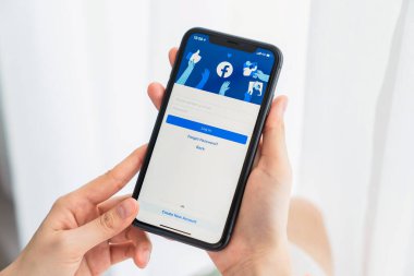 Bangkok, Tayland - 09 Ağustos 2020: Kadın eli Apple iphone 11 'de Facebook ekranına basıyor, Sosyal medya bilgi paylaşımı ve ağ paylaşımı için kullanıyor.