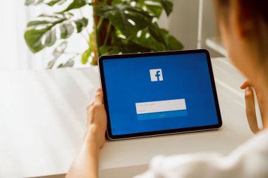 Bangkok, Tayland - 09 Ağustos 2020: Kadın dijital tableti tutuyor ve Facebook ekranına elmalı ipad ve sosyal medya bilgi paylaşımı ve ağ paylaşımı için basıyor.