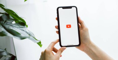 Bangkok, Tayland - 09 Ağustos 2020: Kadın eli Apple iPhone 'da Youtube uygulama simgelerini görüntülüyor. YouTube popüler bir çevrimiçi video paylaşım sitesidir..
