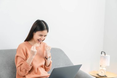 Genç Asyalı kadın dijital dizüstü bilgisayar kullanıyor ve başarı için heyecanlı..