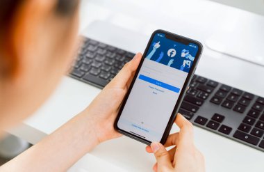 Bangkok, Tayland - 30 Ağustos 2020: Kadın eli Apple iphone 11 'de Facebook ekranına basıyor, Sosyal medya bilgi paylaşımı ve ağ paylaşımı için kullanıyor