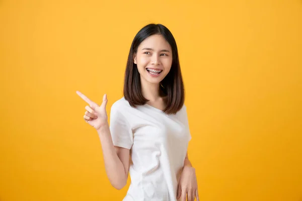 Gülümseyen Asyalı Kadın Ayağa Kalkıp Turuncu Arka Planı Işaret Ediyor — Stok fotoğraf