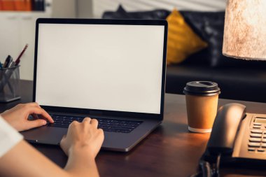 Bilgisayar reklamı koymak için boş bir ekran dizüstü bilgisayar. Elinde kahve fincanı tutan ve ofiste masa başında oturan bir adam..
