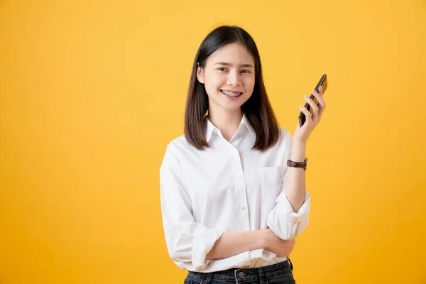 Alegre Hermosa Mujer Asiática Sosteniendo Teléfono Inteligente Sobre Fondo Amarillo — Foto de Stock