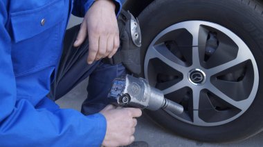 Tamirci (erkek) tekerleği tamir ediyor