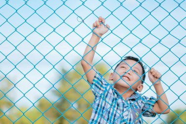 Çocuğun duygusal ifade ile çitin arkasında duruyor.