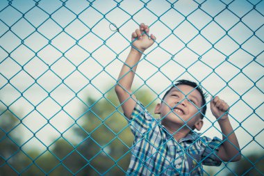 Çocuğun duygusal ifade ile çitin arkasında duruyor.