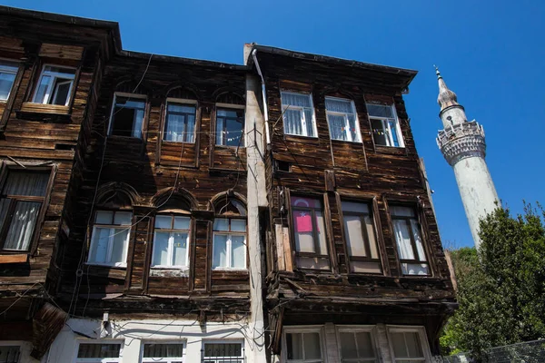 Türkiye, Istanbul-3 Mayıs 2019: Nuruosmaniye semtinde Istanbul 'un eski sokakları. Pencerede bayraklı eski ahşap binanın cephe. Arkasında Lone minare